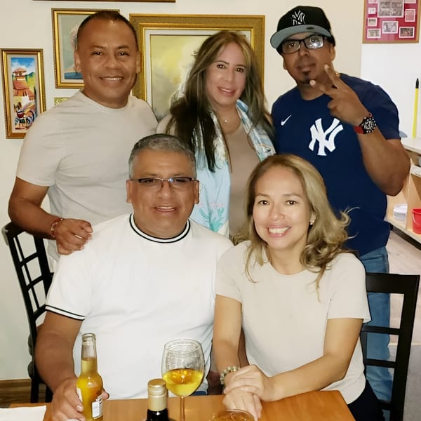 Five smiling adults, three men and two women, posing together at a table in a Peruvian restaurant.