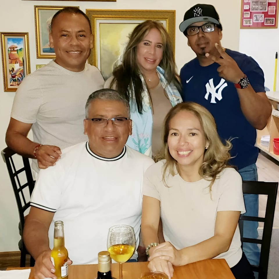 Five smiling adults, three men and two women, posing together at a table in a Peruvian restaurant.
