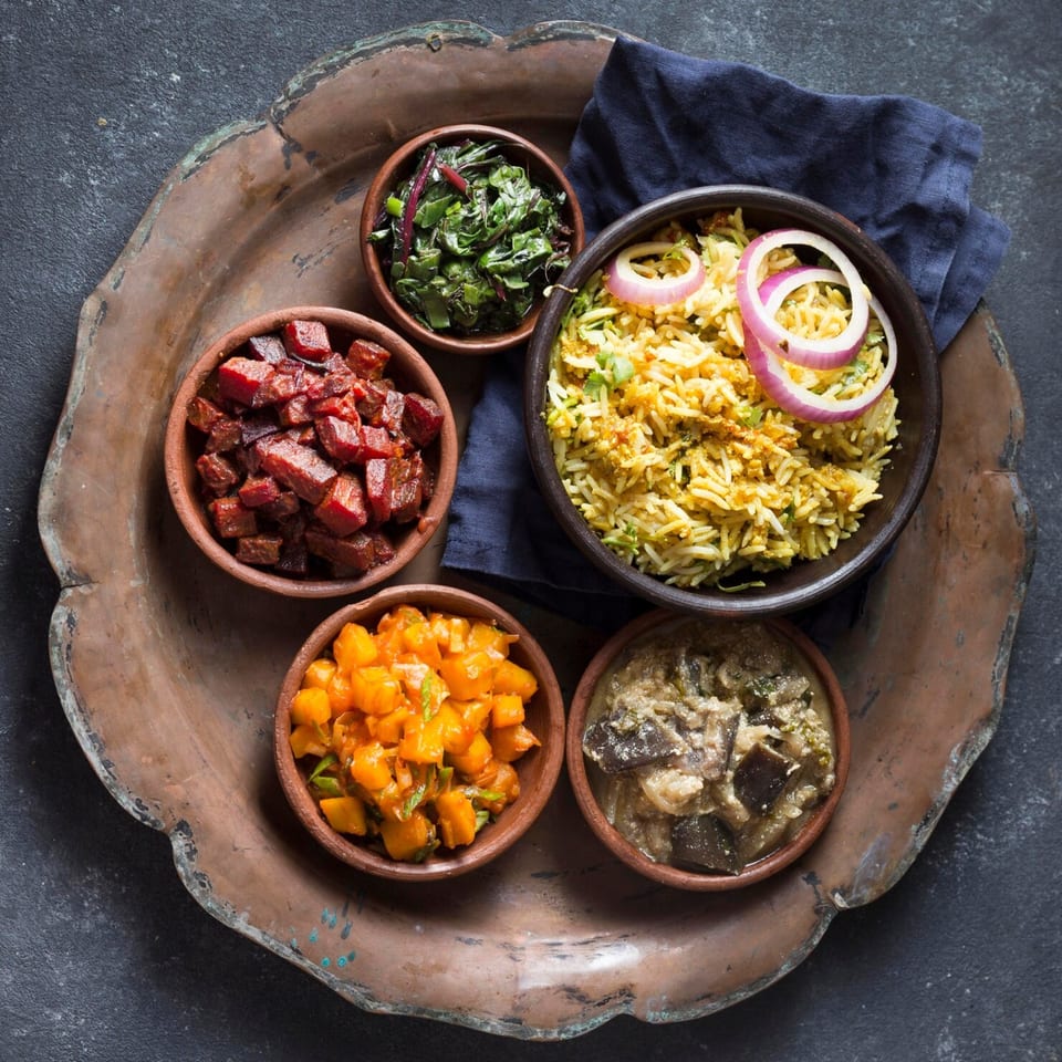 Overhead view of five small bowls of Peruvian food on a rustic copper tray.